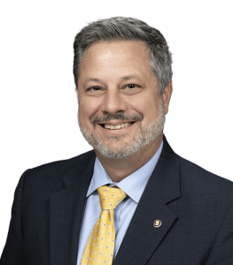 Stephan Picard, President and COO of Digital Consultants, smiling in suit with yellow tie.